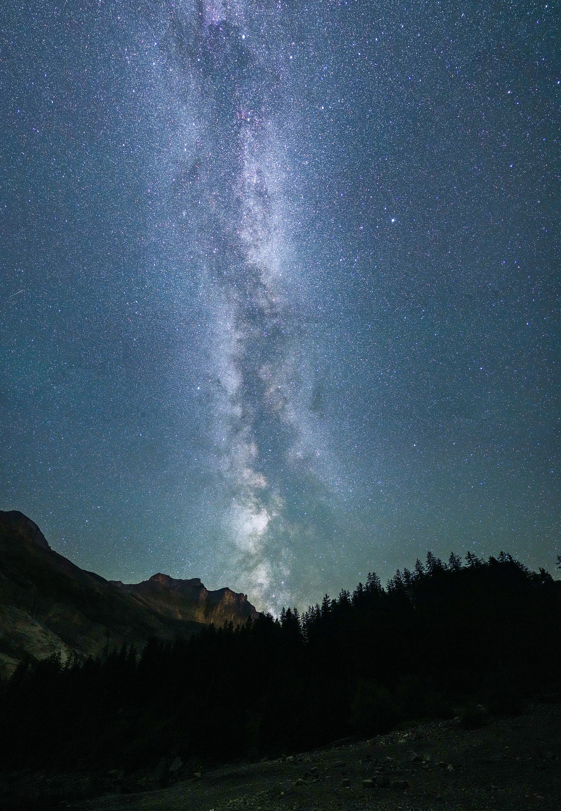 A starfield with the Milky Way over a dark horizon